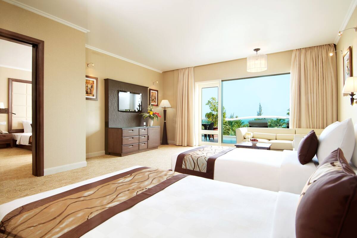 Een hotelkamer met twee bedden, een televisie, een bureau en uitzicht op de omgeving.