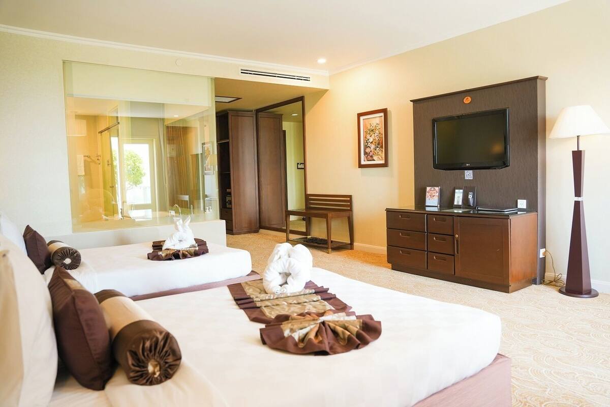 Een hotelkamer met twee bedden, een televisie, een bureau en een spiegel.
