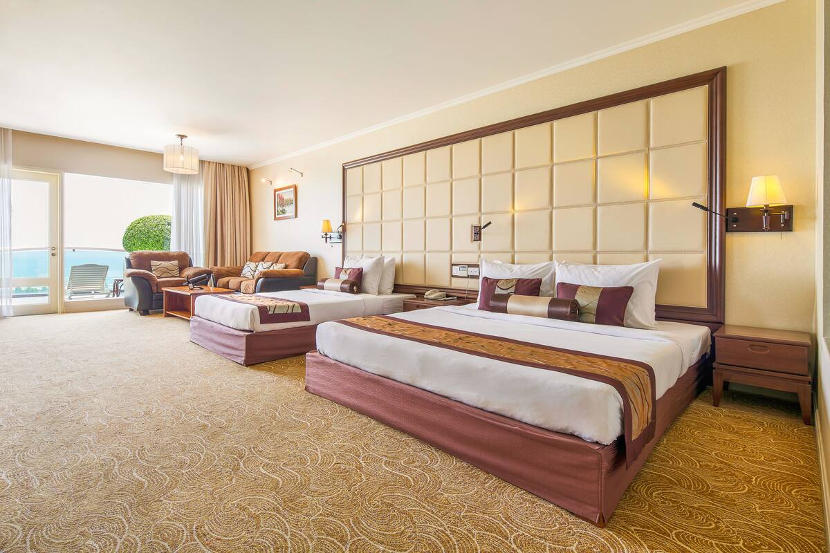 Una habitación de hotel con dos camas, un sofá, una mesita y una mesita de noche.