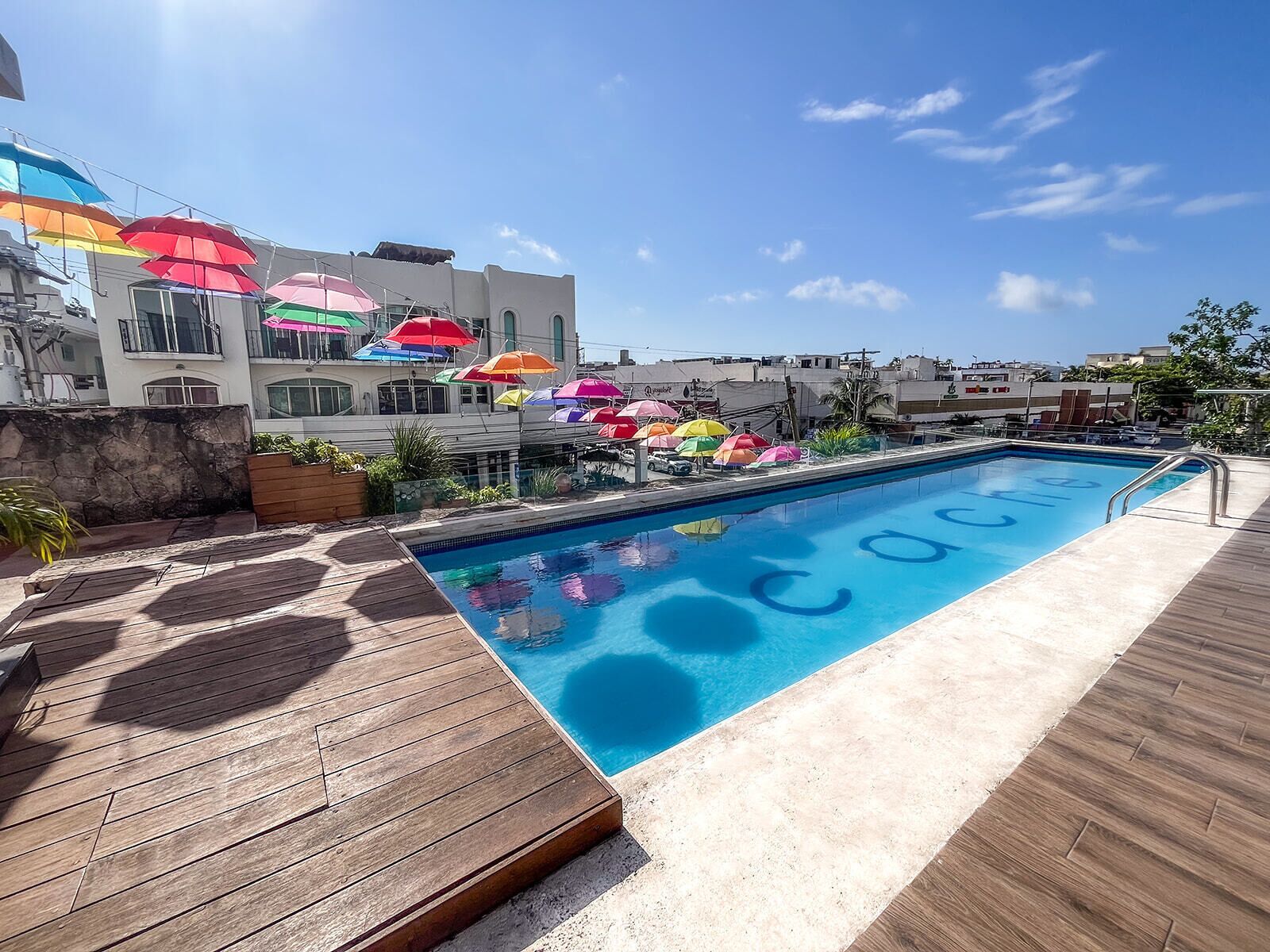 A swimming pool with colorful umbrellas and a wooden deck.