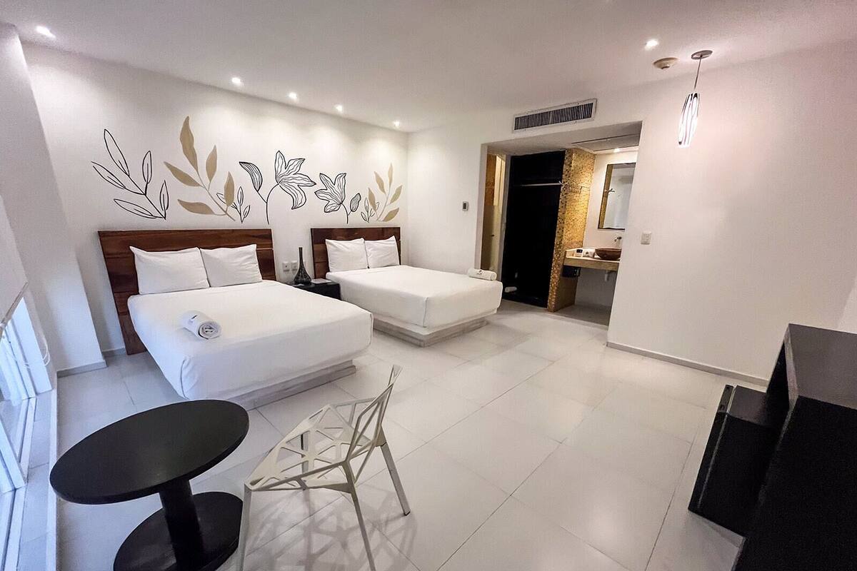 Une chambre d’hôtel moderne avec deux lits, une petite table à manger et un coin cuisine.