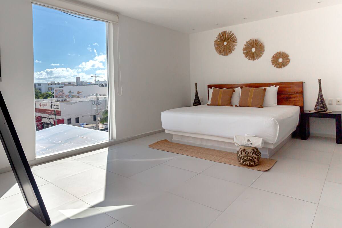 Une chambre d’hôtel moderne avec un grand lit, une vue sur la ville et des œuvres d’art décoratives au mur.