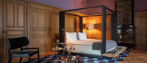 A bedroom with a four-poster bed, a wooden cabinet, and a checkered floor.