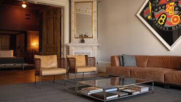 A modern living room with a glass coffee table, leather sofa, and wicker chairs.