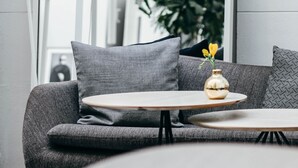 Un interior moderno con un sofá gris, una mesita redonda y una lámpara de pie decorativa.
