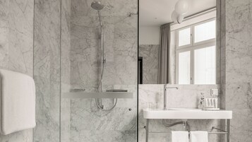 Un baño moderno con cabina de ducha acristalada, un lavamanos blanco y un espejo grande.