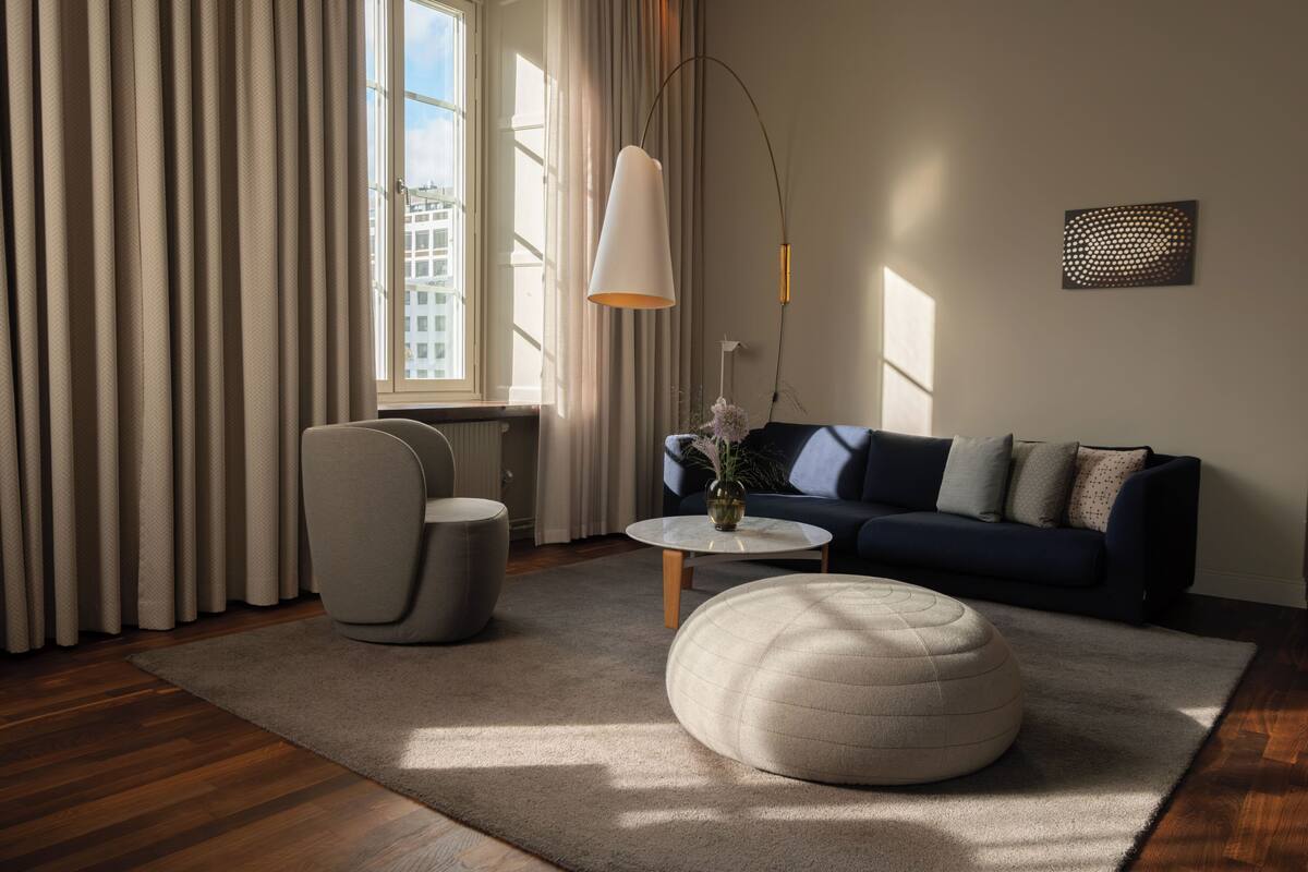 A modern living room with a sofa, ottoman, and a coffee table.