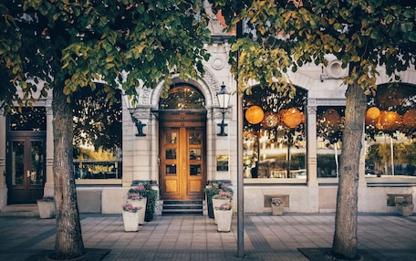 A building with a wooden door, large windows, and potted plants.