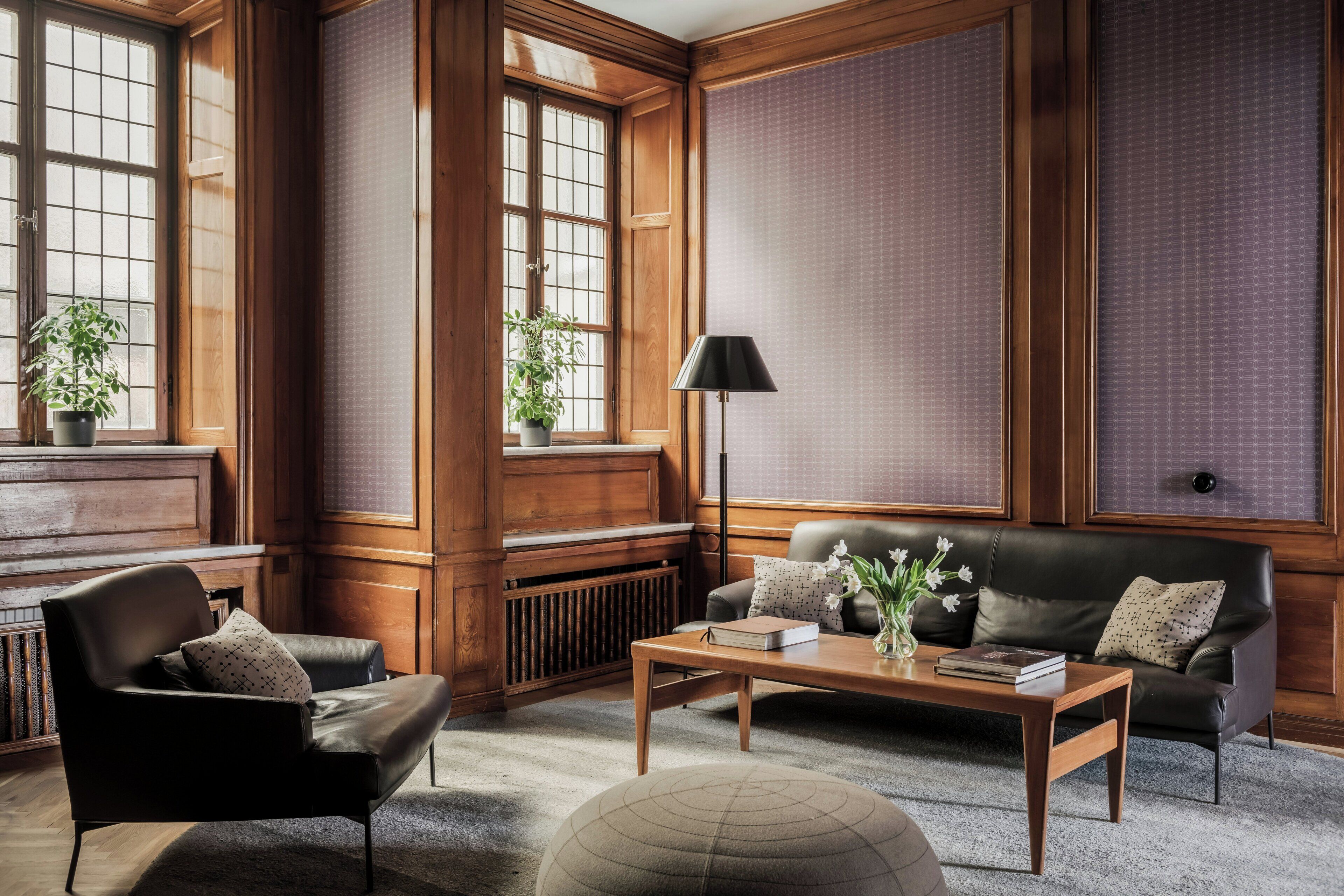 A room with a leather sofa, a wooden coffee table, a black floor lamp, and a radiator.