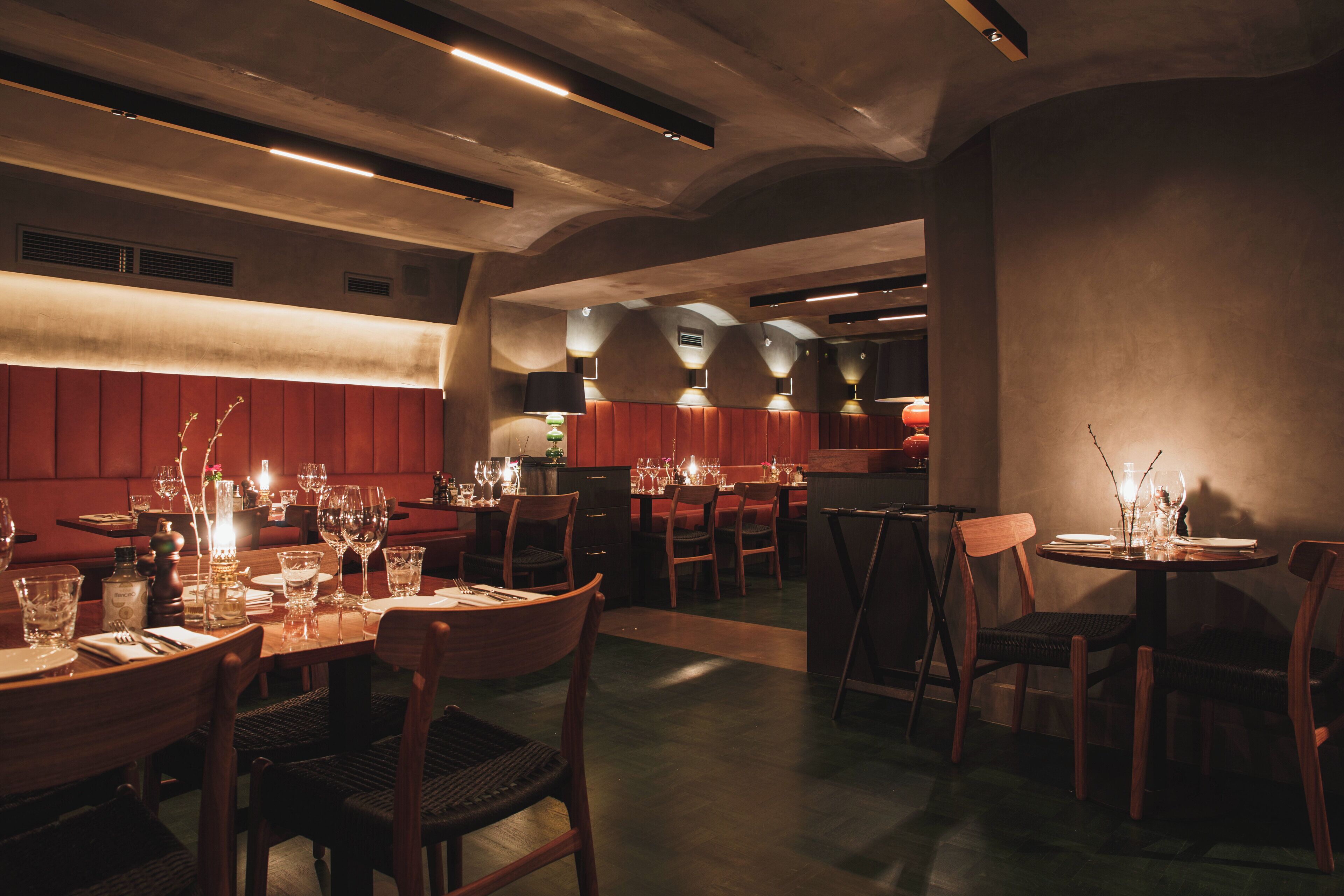 A restaurant with multiple tables set for dining, featuring wooden chairs and a warm ambiance.
