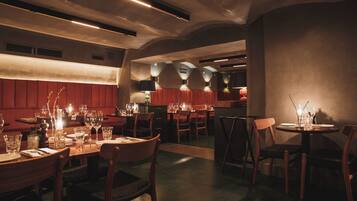 A restaurant with multiple tables set for dining, featuring wooden chairs and a warm ambiance.