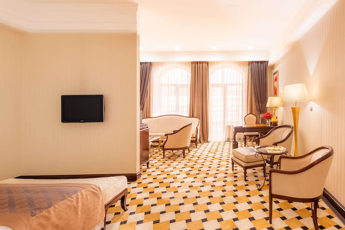 Una habitación de hotel con cama, escritorio, dos sillas, televisor y piso con diseño.