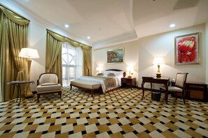 A hotel room with a checkered floor, a bed, two chairs, a desk, and two lamps. - Royal Tulip Almaty (Almaty)