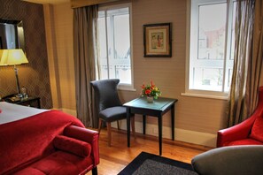 A hotel room with a bed, a desk, a chair, and a window with curtains.
