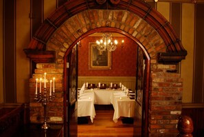 A dining area with a brick archway leading to a table set for a meal.