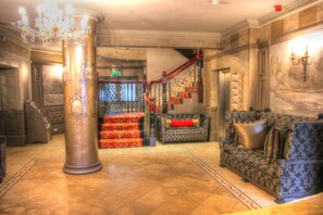 A grand lobby with a large column, a staircase, and a plush sofa.