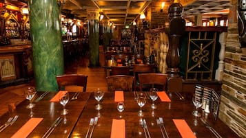 L’intérieur d’un restaurant avec des tables et des chaises en bois, ainsi qu’un coin bar.