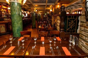 A restaurant interior with wooden tables, chairs, and a bar area.