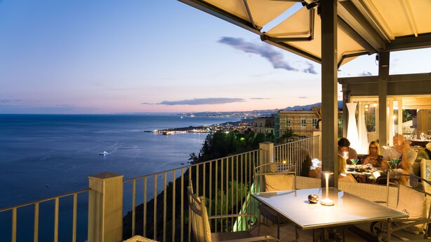 Une terrasse avec une table et des chaises donnant sur la mer.