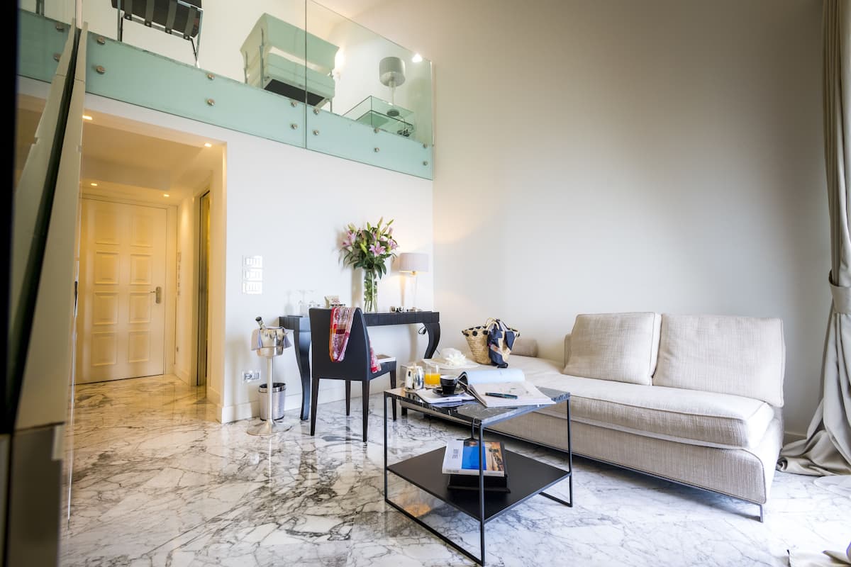 A modern living room with a sofa, a coffee table, and a dining area with a chair and table.