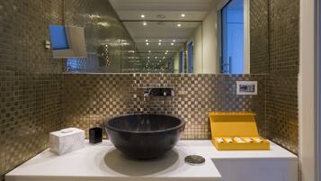 A modern bathroom with a large black basin, a white marble box, and a yellow soap dish.