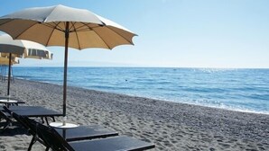 Une plage avec des chaises longues et des parasols.