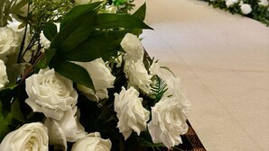 Una zona de recepció amb una taula de recepció llarga, cadires i un arranjament floral decoratiu.