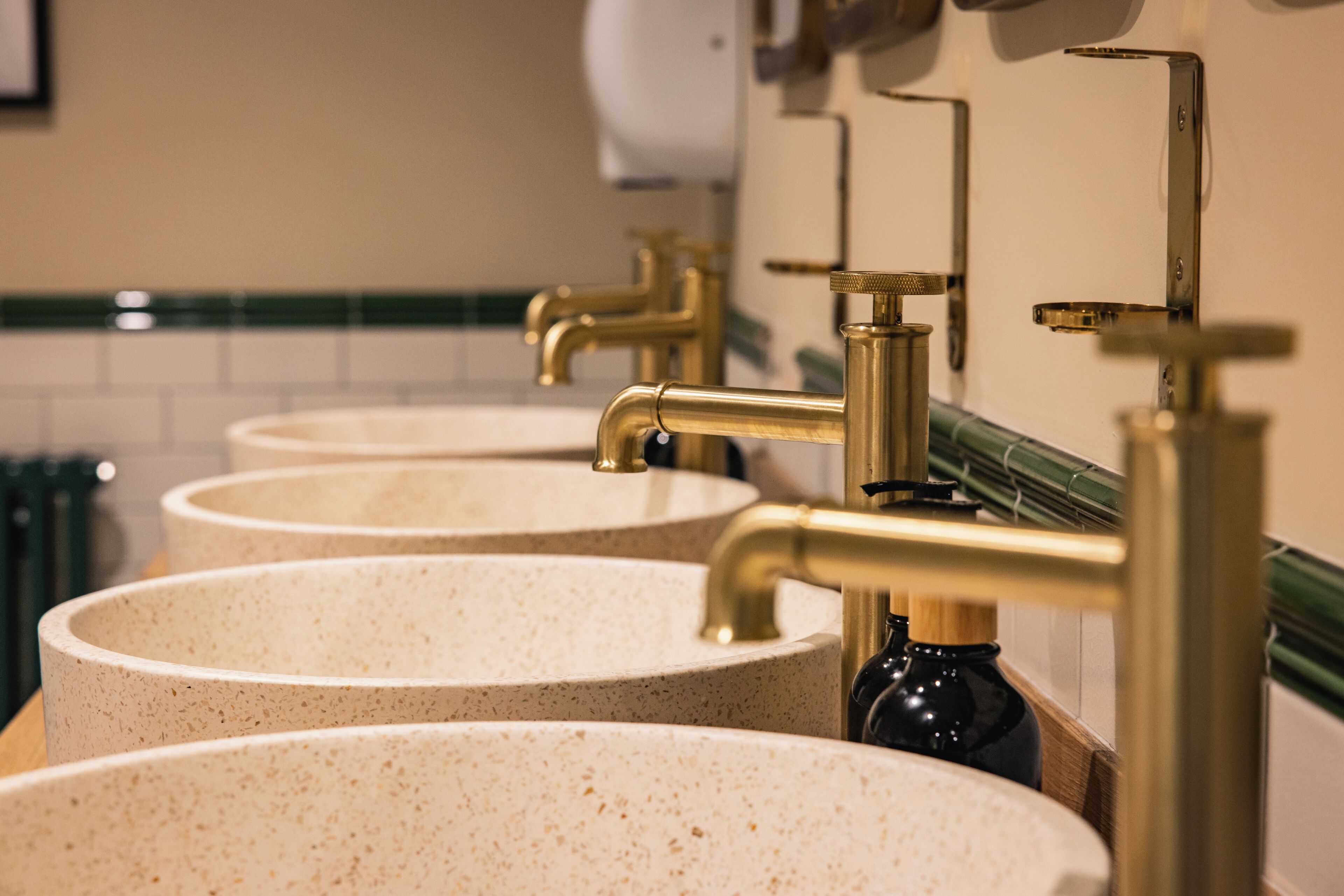 A row of sinks with gold faucets in a restroom.