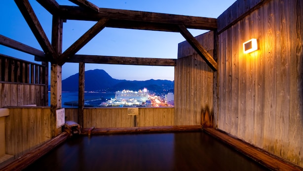 A wooden interior with a view of a cruise ship and mountains in the background.