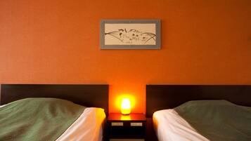 A hotel room with two beds, a nightstand with a lamp, and a framed artwork on the wall.