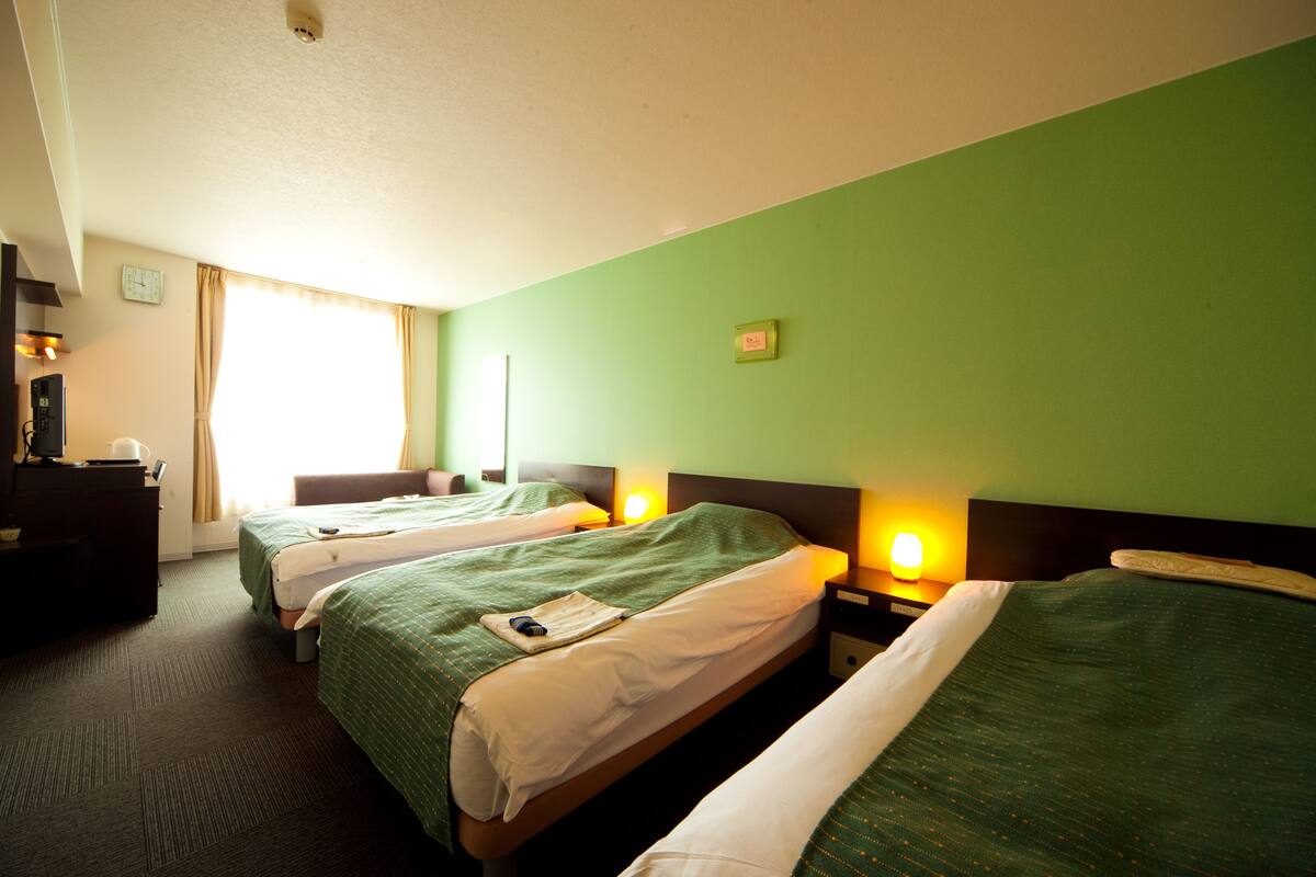 A hotel room with two beds, a desk, and a chair.