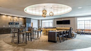 A spacious hotel lobby with a central bar area, seating arrangements, and a large window providing natural light. - Springhill Suites by Marriott Waco Woodway (Waco)