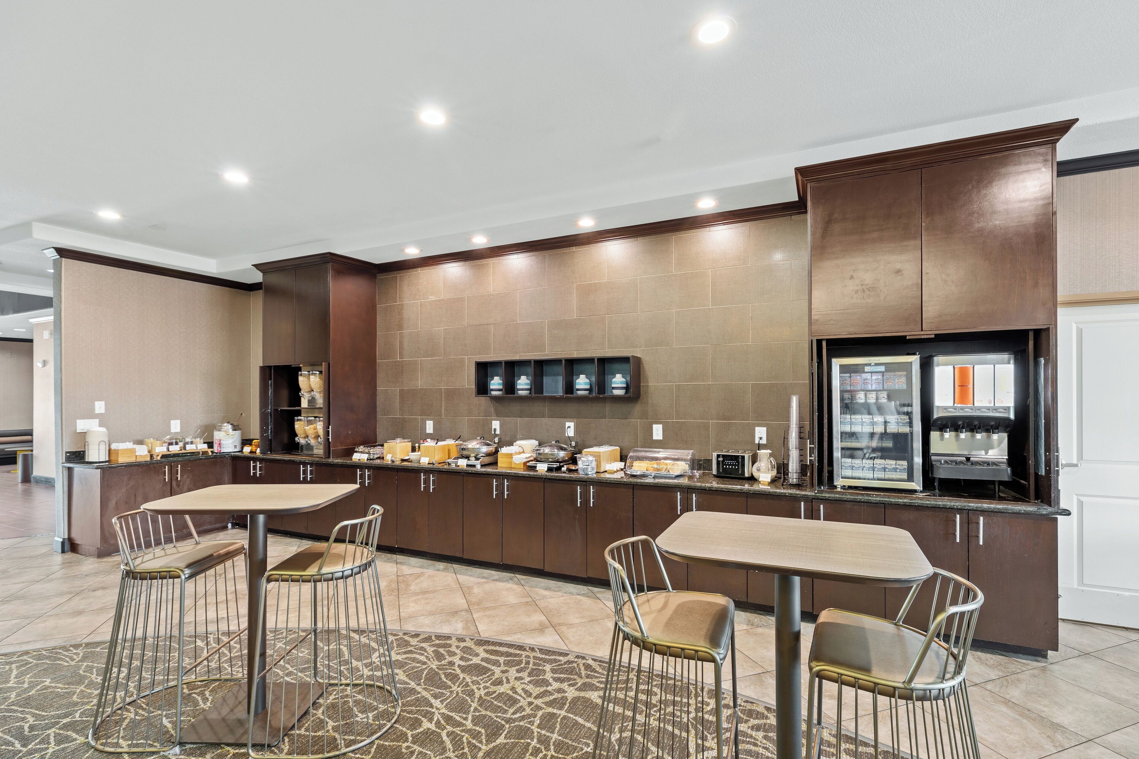 Uma cozinha moderna com ilha central, banquetas e geladeira.