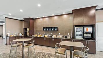Uma cozinha moderna com ilha central, banquetas e geladeira.