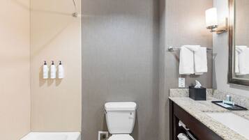 Une salle de bain équipée de toilettes, d’un lavabo, d’un miroir et d’un porte-serviettes.