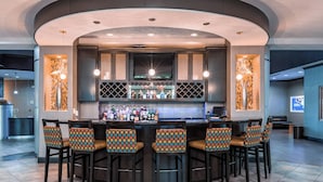 A bar area with a curved ceiling, a central bar counter, and six bar stools with patterned cushions. - Springhill Suites by Marriott Waco Woodway (Waco)