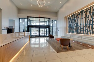 A modern reception area with a glass door entrance, a reception desk, seating area, and a decorative wall.