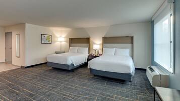 Habitación de hotel con dos camas, un ventanal grande y piso alfombrado.