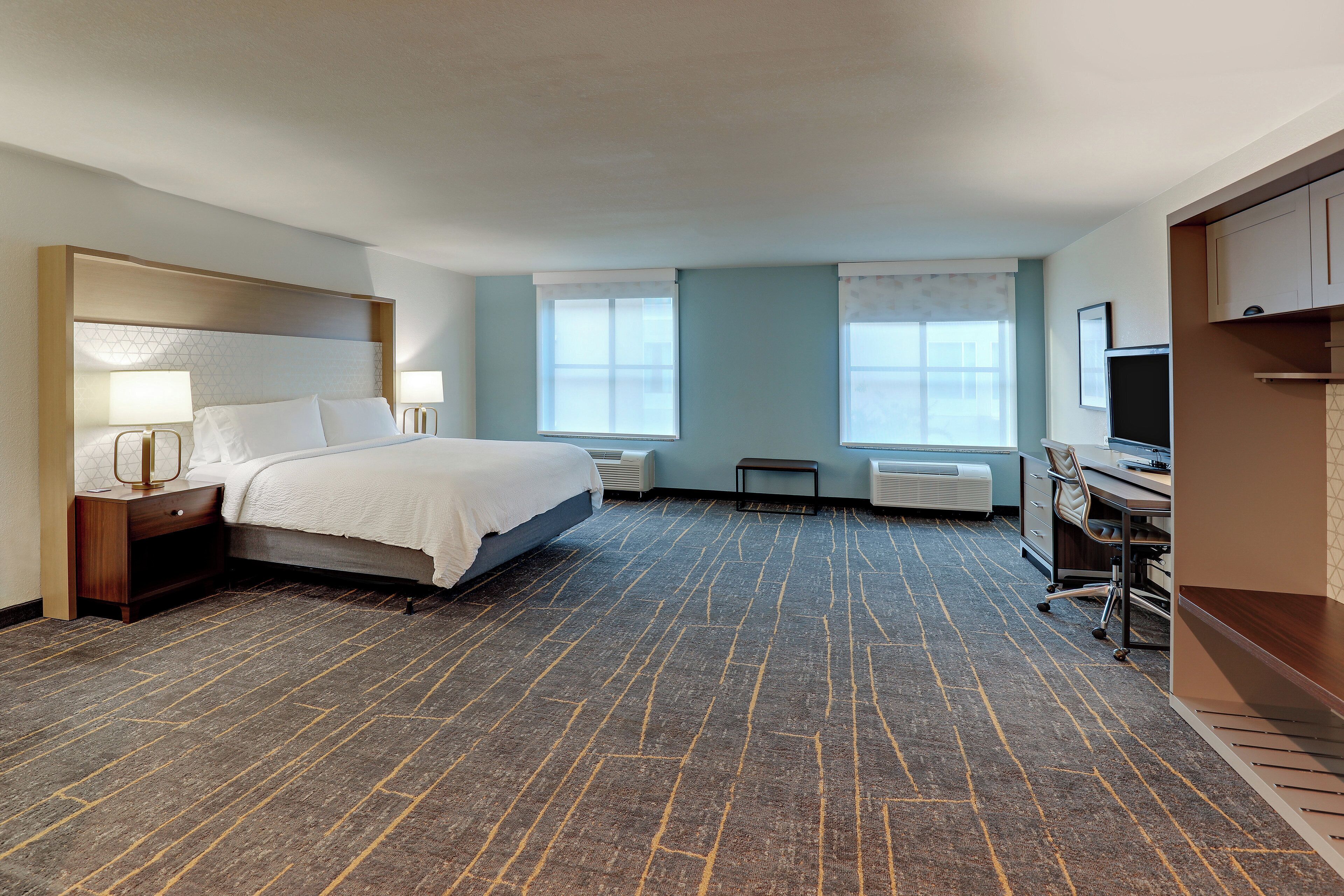 Ein Hotelzimmer mit Bett, Nachttischen, Schreibtisch, Stuhl und Fernseher.