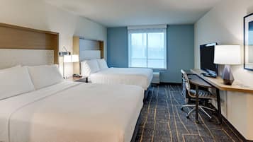 A hotel room with two beds, a desk with a computer, a TV, and a window with a view.