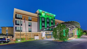 Ett Holiday Inn-hotell med en modern fasad, stora fönster och en ingång som är skyddad av ett tak.