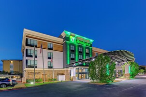 Un hotel Holiday Inn con fachada moderna, ventanas amplias y un acceso cubierto.