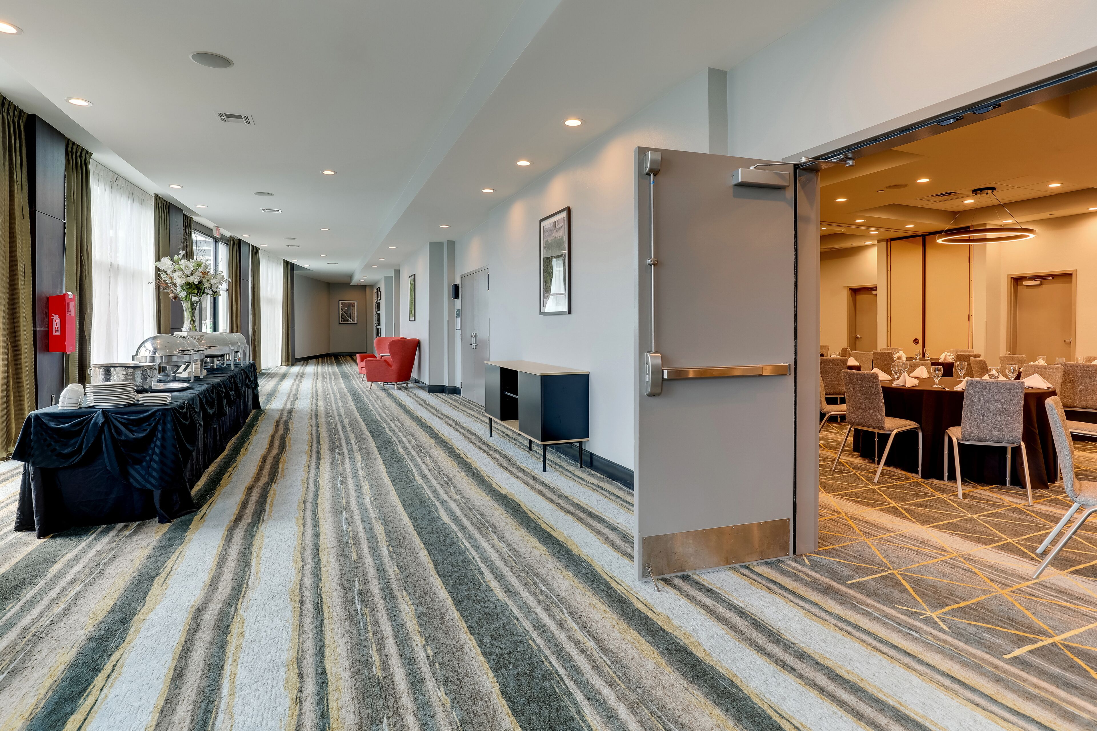 Un pasillo de hotel con una larga mesa dispuesta para comer, una zona de recepción y una sala de conferencias.