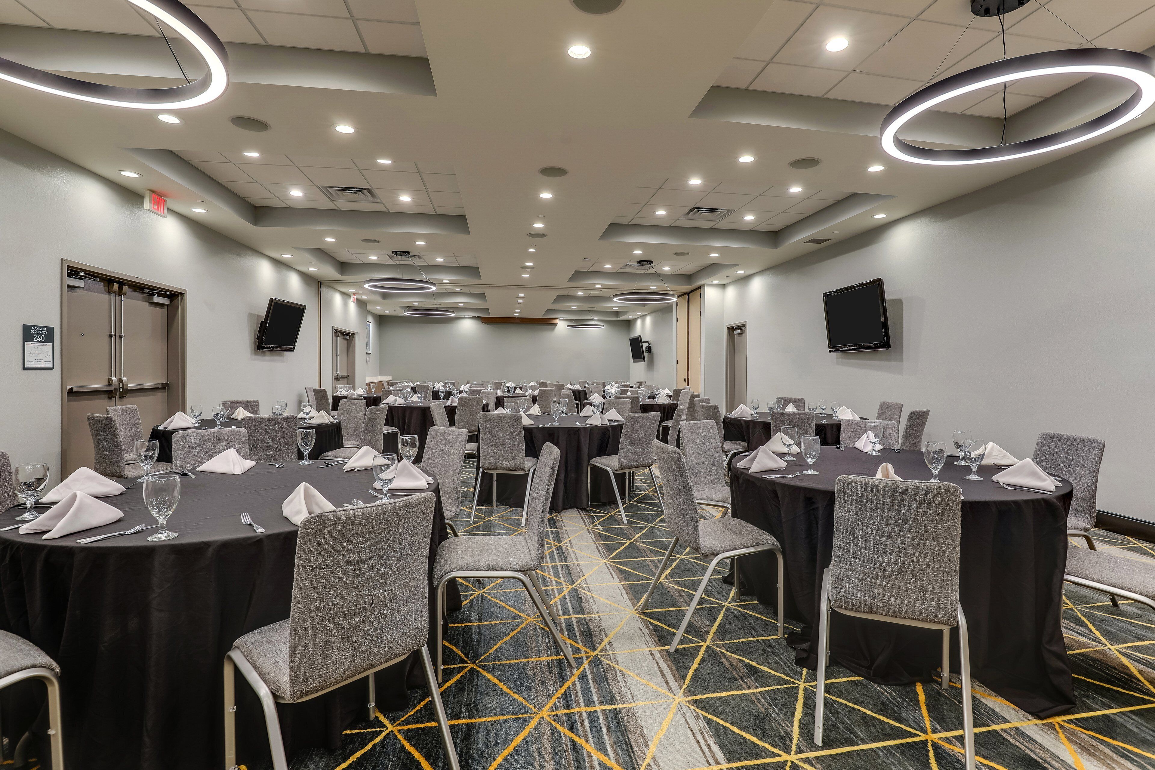 A conference room with round tables, grey chairs, and black tablecloths.