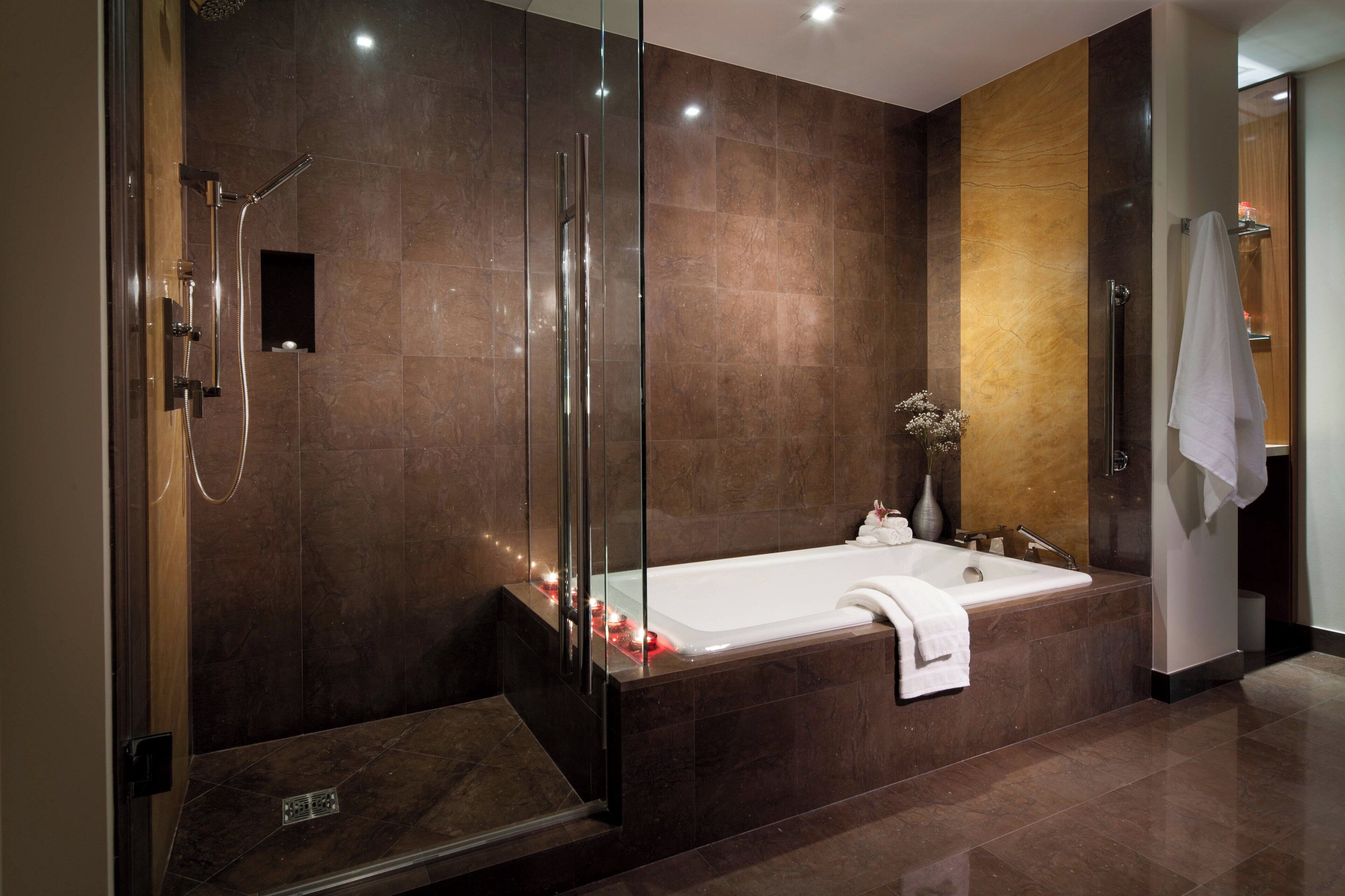 Une salle de bain moderne dotée d’une douche à parois de verre, d’une baignoire sur pieds et d’un sol carrelé en marbre.