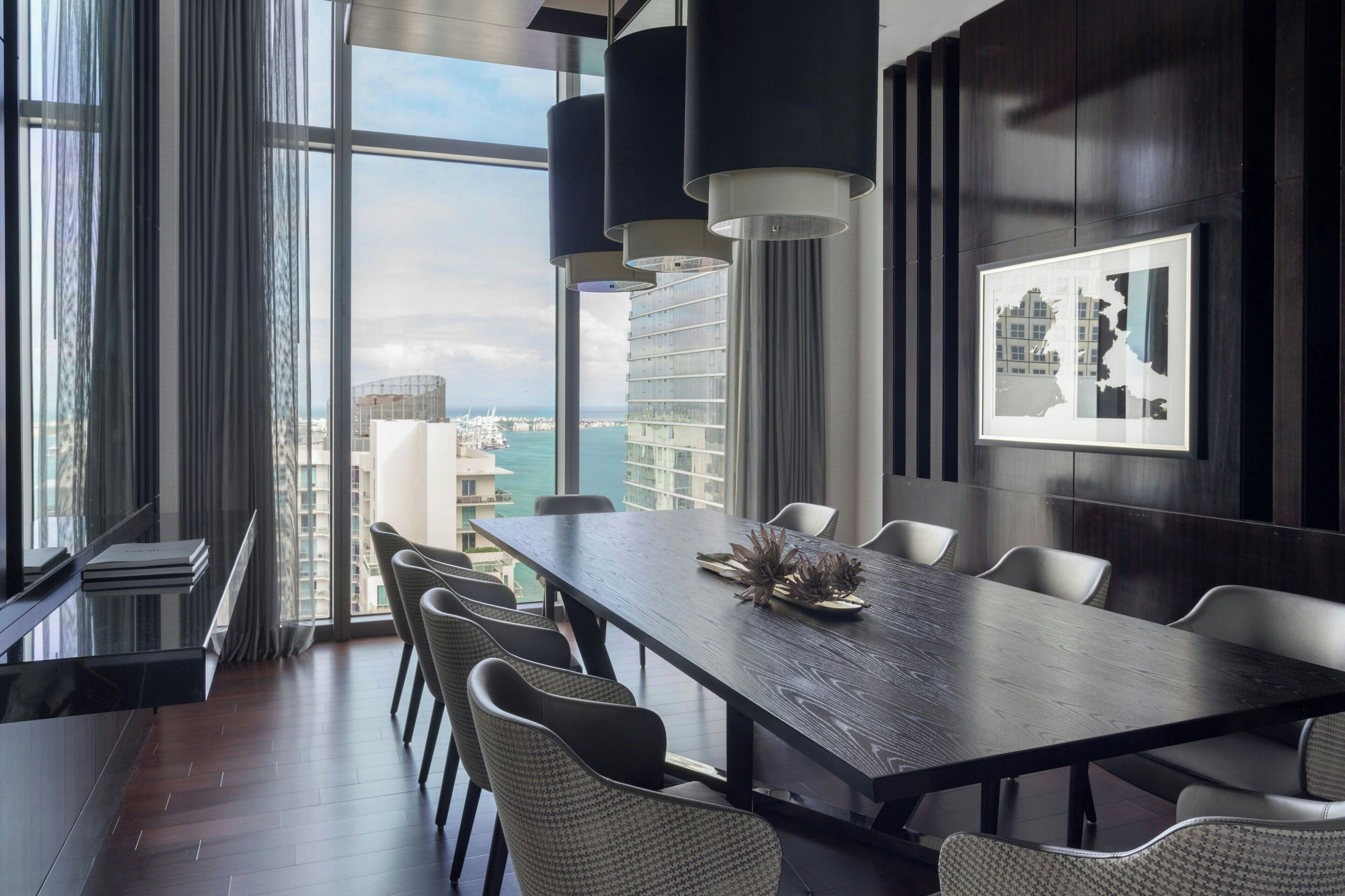A modern conference room with a large table, comfortable chairs, and a city view through large windows.