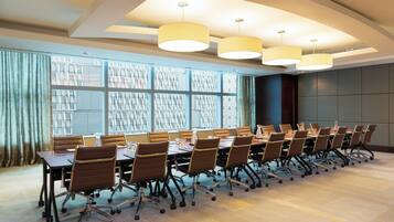A conference room with a long table, chairs, and overhead lighting.