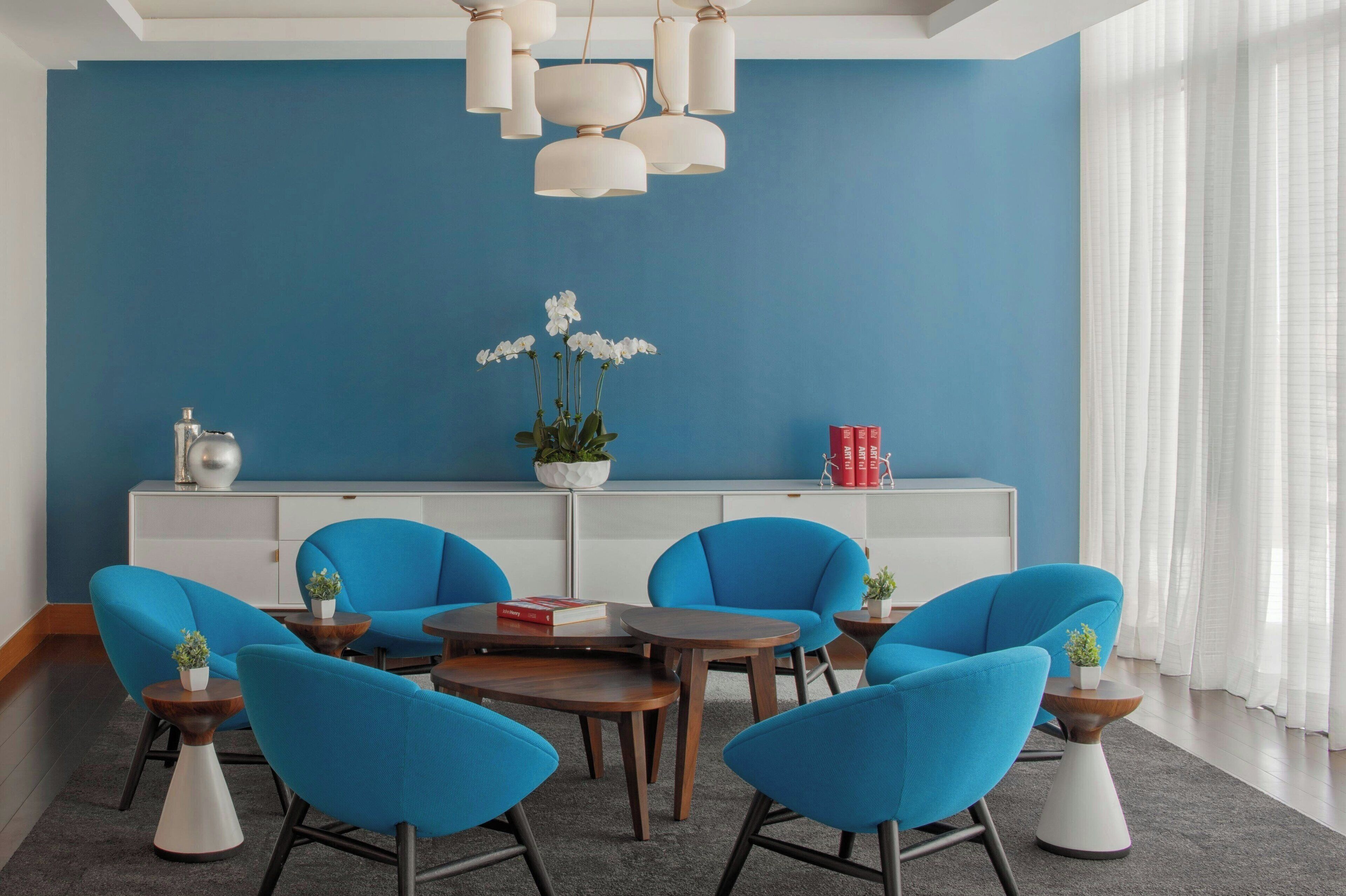 A modern living room with blue walls, a white console table, and matching blue chairs.