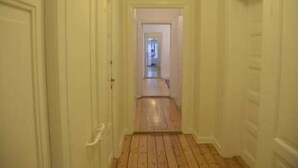 Un pasillo estrecho con suelo de madera y paredes blancas.