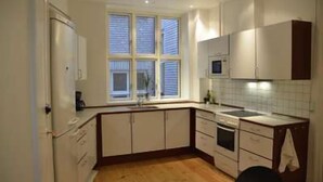 Cocina compacta con armarios blancos, horno integrado y microondas.